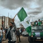 Grupo de pessoas caminhando na rua segurando bandeira na África