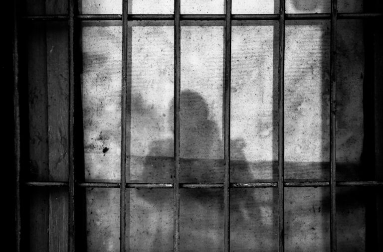 Sombra de pessoa atrás de grades prisão