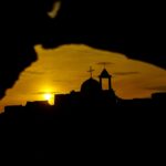 Silhouette of a church at sunset through a dark frame.
