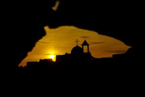 Silhouette of a church at sunset through a dark frame.