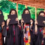 a group of women holding up black paper