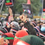 Grande grupo de pessoas segurando cartazes em protesto